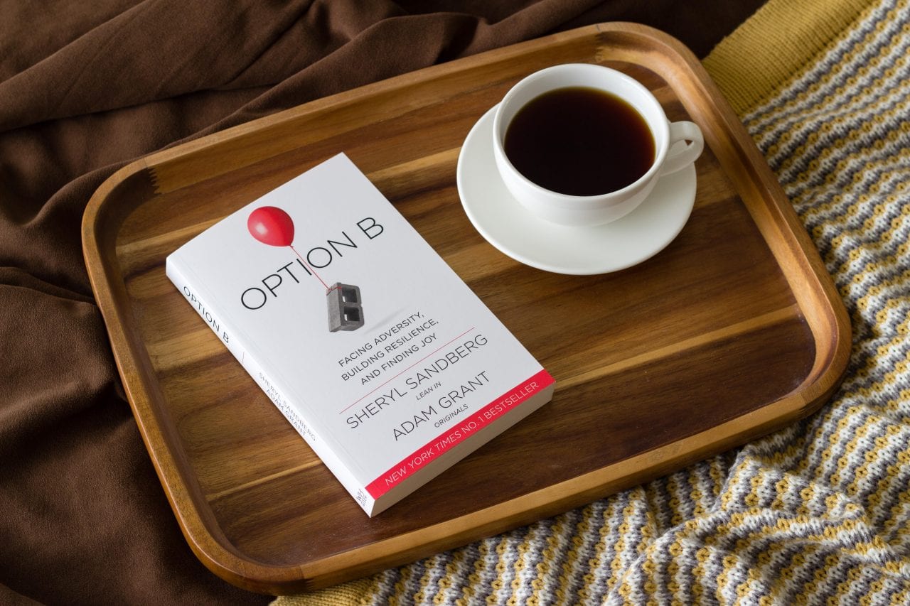 The book "Option B" and a cup of coffee on a wooden tray