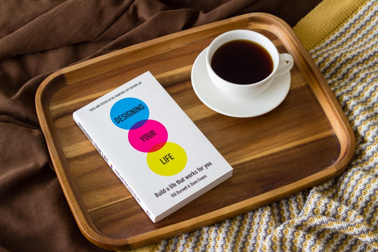 The book "Designing Your Life" and a cup of coffee on a wooden tray