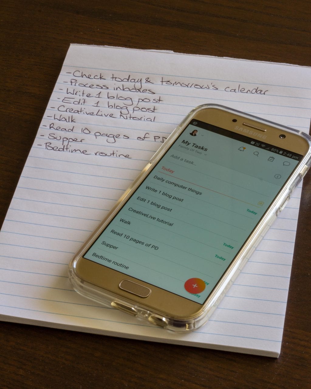 A paper notepad and a smartphone, both featuring to-do lists