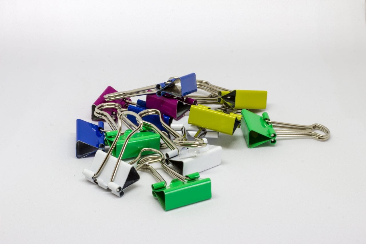 A pile of small, colourful bulldog clips