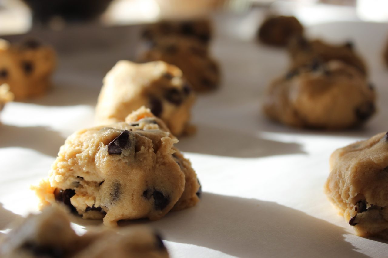 Lumps of cookie dough arranged in rows on a baking sheet