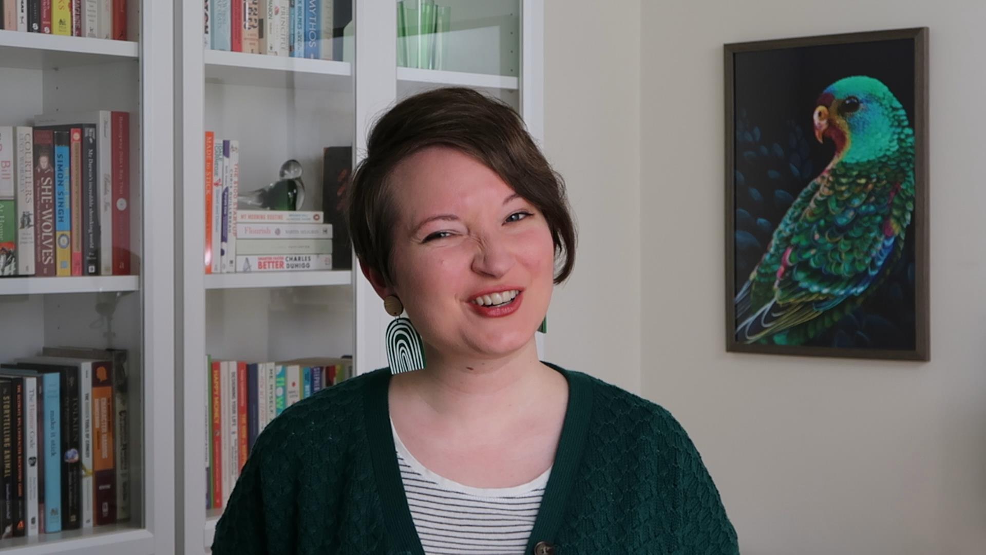 Christina wearing a green cardigan, looking sceptically at the camera