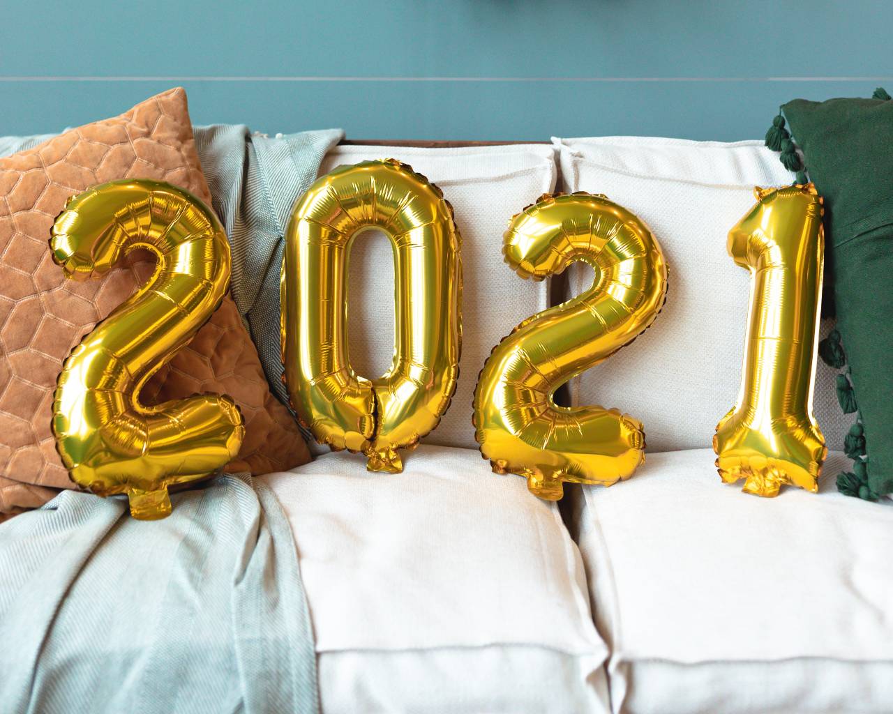 Four gold inflatable balloons resting on a couch spell out "2021"