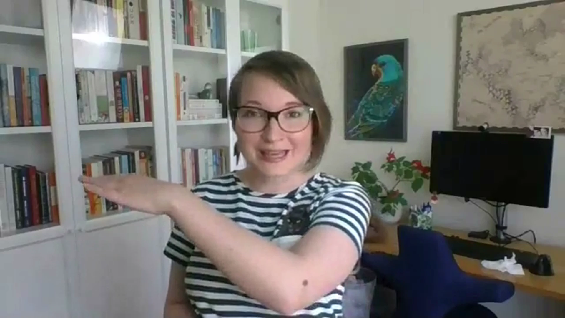 Christina is midway through talking animatedly, and is gesturing an upward slope with her left arm. She is wearing a stripey green and white t-shirt.