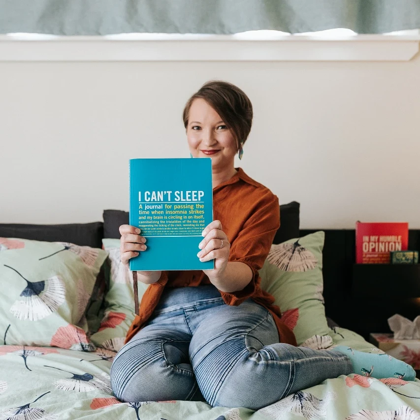 Christina sitting on her bed holding up a book entitled "I can't sleep"