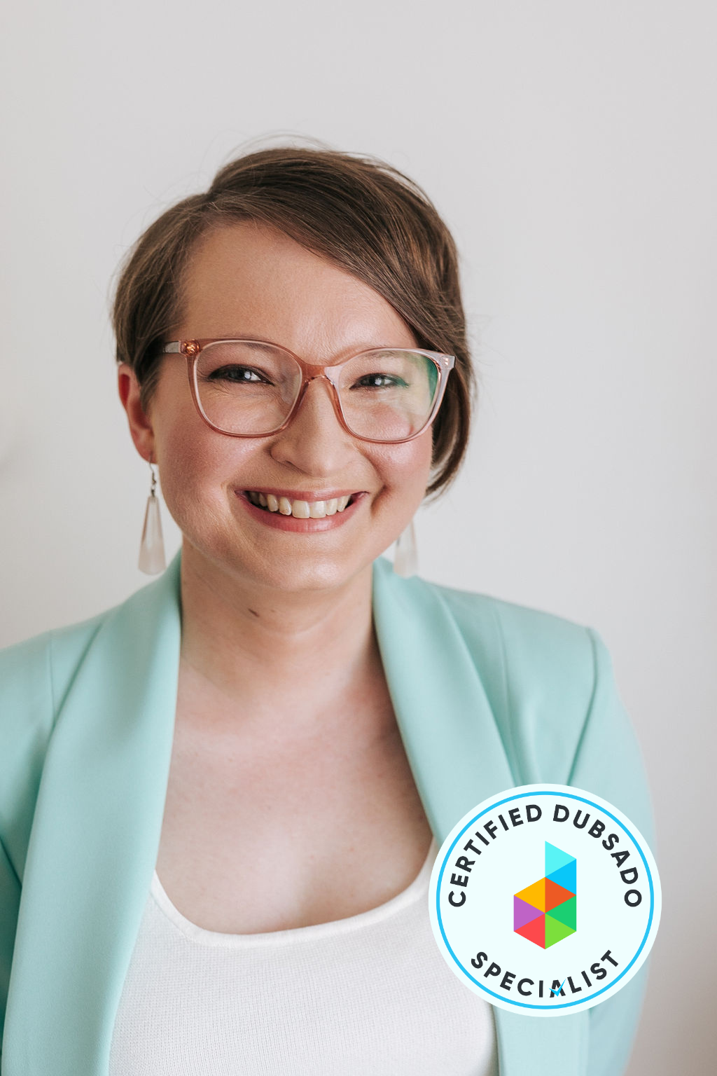 Christina is a light-skinned woman with short, light brown hair. She's wearing a light green blazer, glasses, and a wide smile. In the foreground is the Certified Dubsado Specialist badge.
